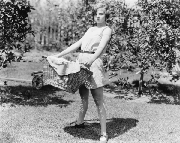 Mujer joven llevando una cesta de ropa sucia —  Fotos de Stock