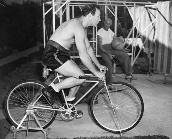 Man sitter på en stillastående cykel gör övning — Stockfoto