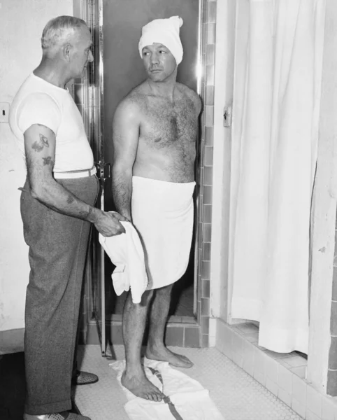 Um homem prestes a tomar banho e um atendente em um banheiro — Fotografia de Stock