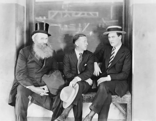Трое мужчин сидят на скамейке — стоковое фото