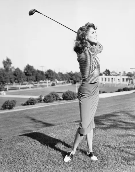 Žena na driving range, kyvná golfovou holí — Stock fotografie