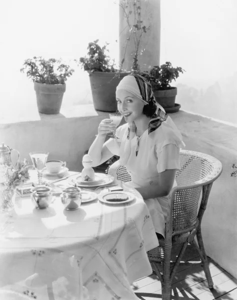 Женщина сидит на веранде и завтракает — стоковое фото