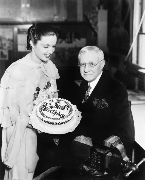 高齢男性に誕生日ケーキを提示する若い女性 — ストック写真