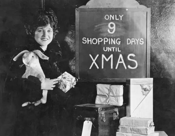 Γυναίκα με δώρα και πινακίδα με αριθμό ημέρες αγορών μέχρι τα Χριστούγεννα — Φωτογραφία Αρχείου