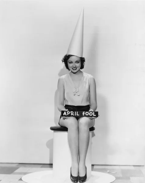 Porträtt av kvinna med aprilskämt tecken bär dumbom cap — Stockfoto