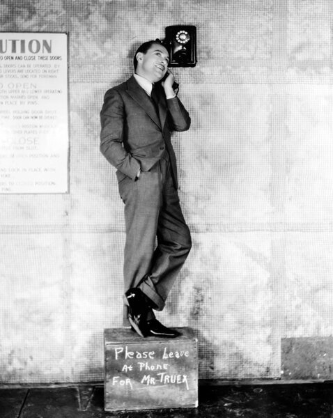 Man standing on a box to reach the telephone