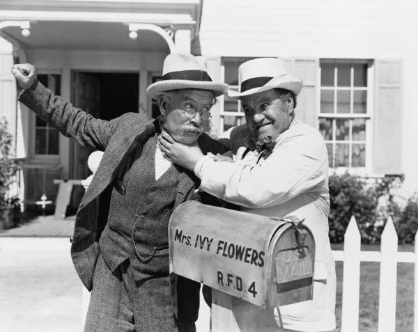 Deux hommes mûrs se battant près d'une boîte aux lettres devant une maison — Photo