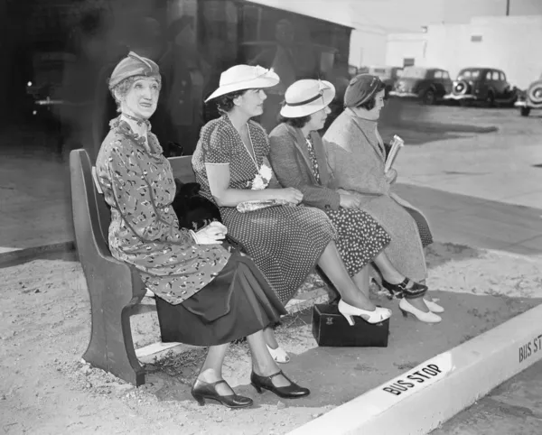 Dört kadın otobüs beklerken bir bankta oturan — Stok fotoğraf