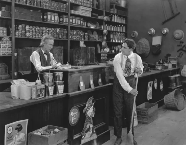 Αφεντικό βλέποντας σαρωτικές πάτωμα εργαζόμενος σε κατάστημα — Φωτογραφία Αρχείου
