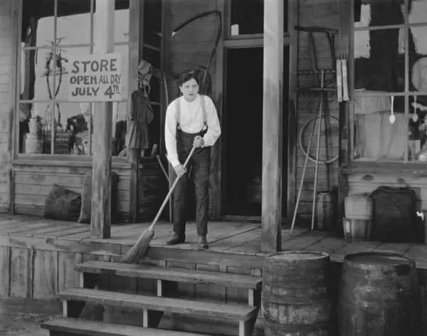 Чоловік підмітає сходи перед магазином — стокове фото