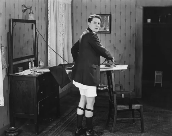 Man in sock garters ironing