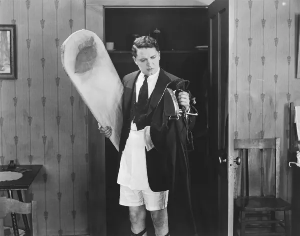 Мужчина в боксерских шортах с утюгом и гладильной доской — стоковое фото
