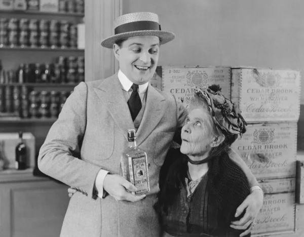 Senior woman looking at man holding gin bottle — Stock Photo, Image