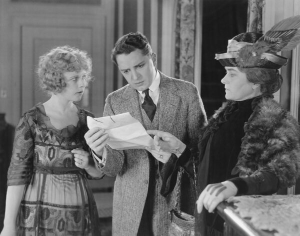 Man reading letter with two women looking over his shoulder
