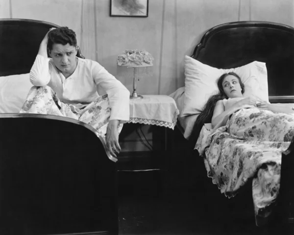 Молодая пара на разных кроватях после боя — стоковое фото
