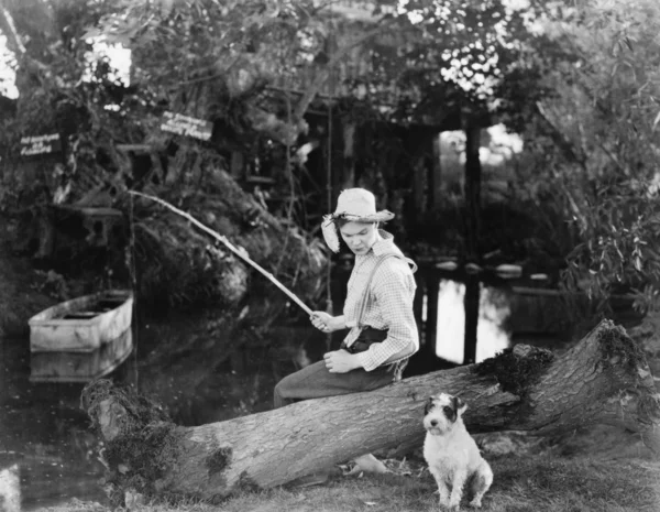 Молодий чоловік рибалить зі своїм собакою — стокове фото