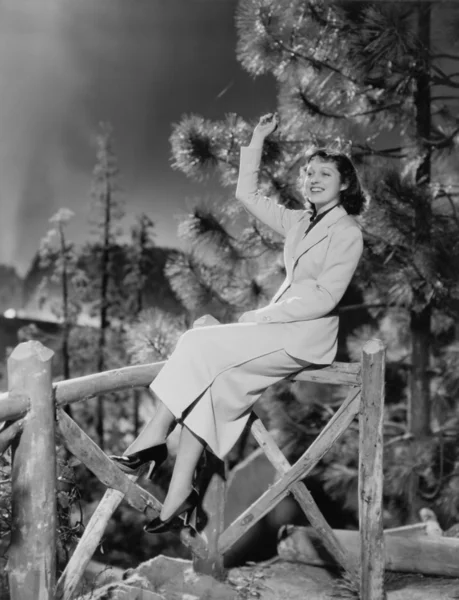 Mujer sentada sobre barandilla de madera — Foto de Stock
