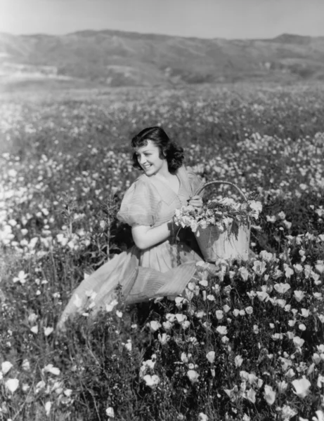 Vrouw verzamelen bloemen in veld — Stockfoto