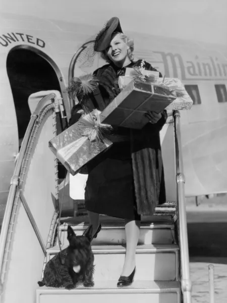 Mulher com presentes subindo escadas de avião — Fotografia de Stock
