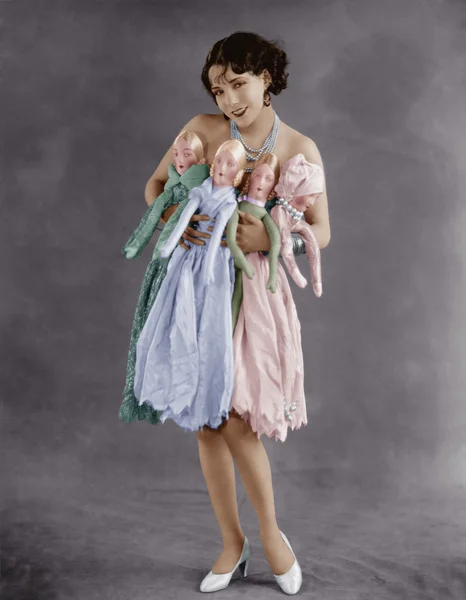Portrét mladé ženy držící čtyři panenky — Stock fotografie