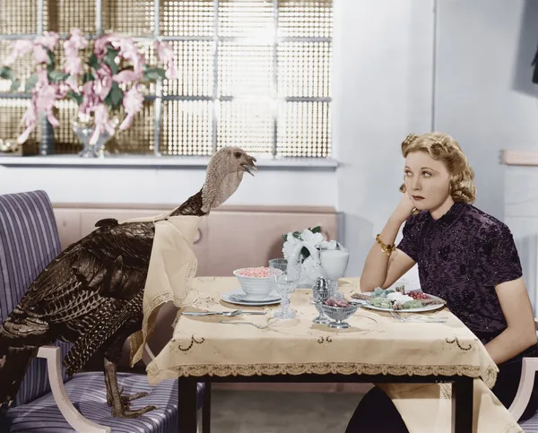 Frau isst Essen am Tisch mit lebendem Truthahn — Stockfoto