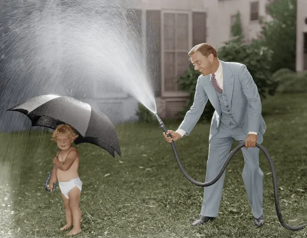 Bambino e papà giocare con tubo in cortile — Foto Stock