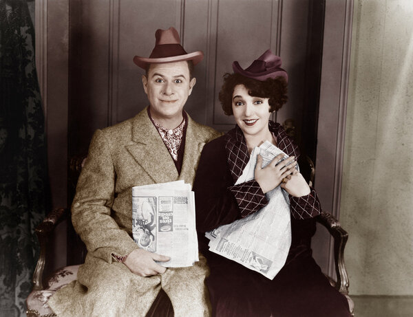 Portrait of smiling couple with newspapers