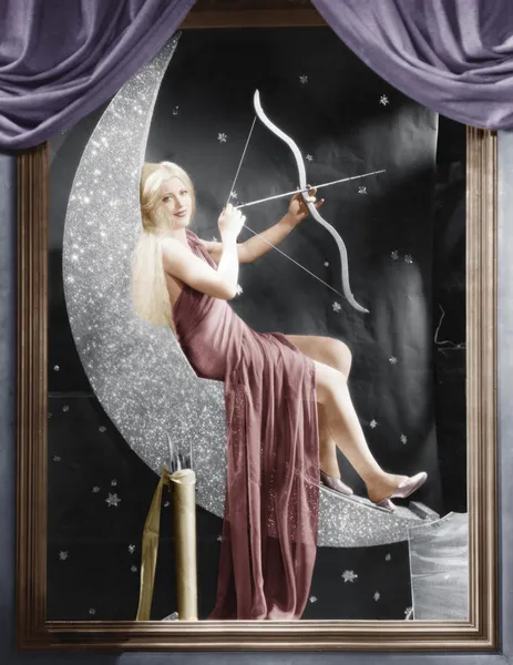 Frau sitzt mit Pfeil und Bogen auf Mondsichel — Stockfoto