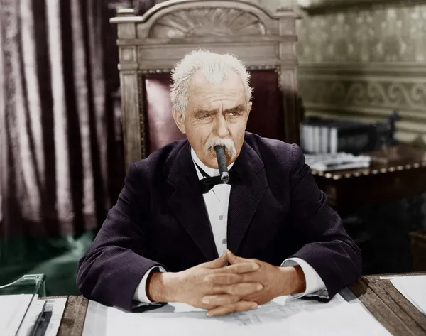 Businessman smoking cigar at desk — Stock Photo, Image