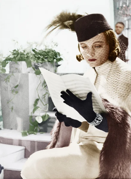 Женщина в шляпе и вуали читает ноты — стоковое фото