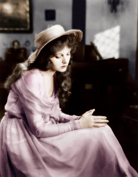 Mujer joven en un sombrero sentado y mirando triste —  Fotos de Stock