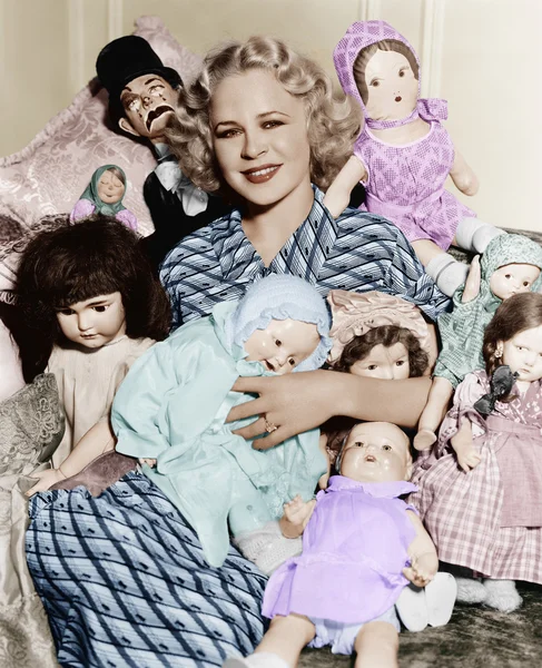 Porträtt av en kvinna omgiven av dockor och leende — Stockfoto