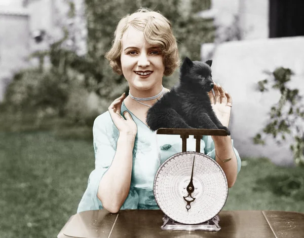 Portrait of a young woman weighing her puppy on a weighing scale — Stock Photo, Image
