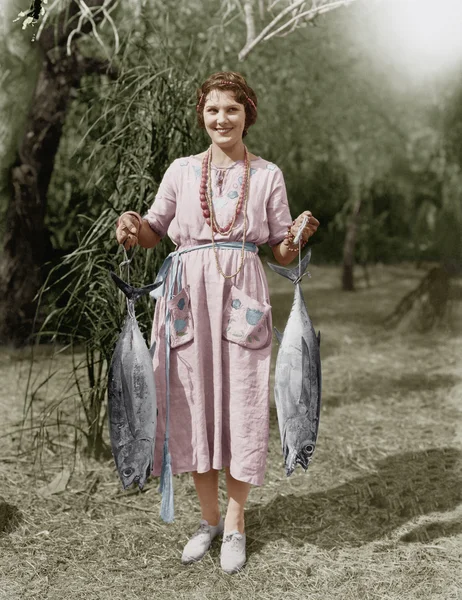 Mujer joven sosteniendo dos peces enormes — Foto de Stock