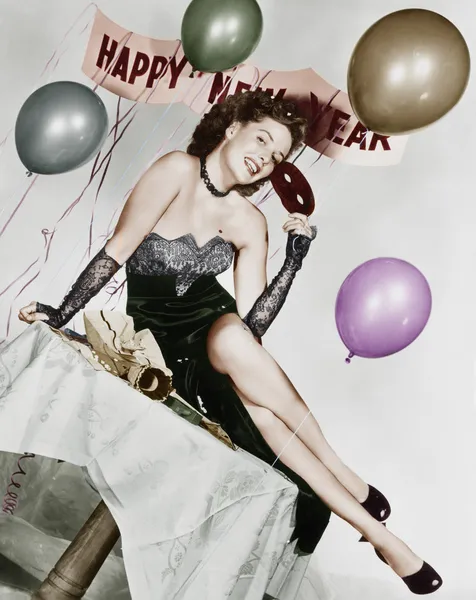 Νεαρή γυναίκα που κάθεται σε ένα τραπέζι με μπαλόνια και σημάδι — Φωτογραφία Αρχείου