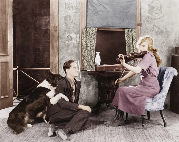 Женщина играет на скрипке для своего парня и собаки — стоковое фото