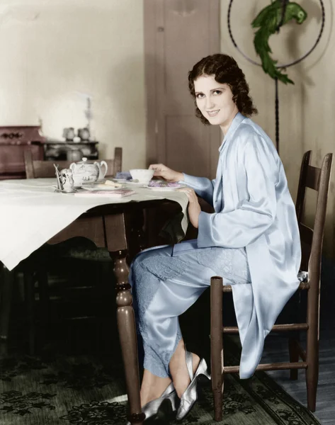 Kahvaltı çay içiyor bir masada oturan genç kadın — Stok fotoğraf