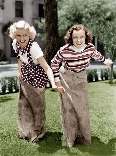 Dos mujeres jugando un juego de carreras de sacos de patatas — Foto de Stock