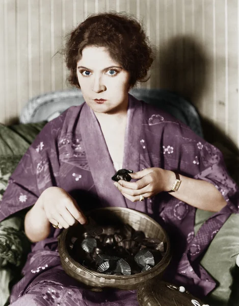 Γυναίκα τρώει σοκολάτες από ένα μπολ — Φωτογραφία Αρχείου
