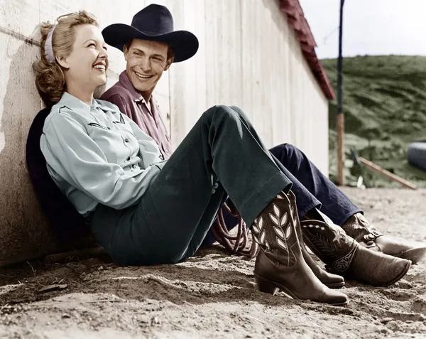 Riendo pareja en traje occidental sentado en el suelo — Foto de Stock
