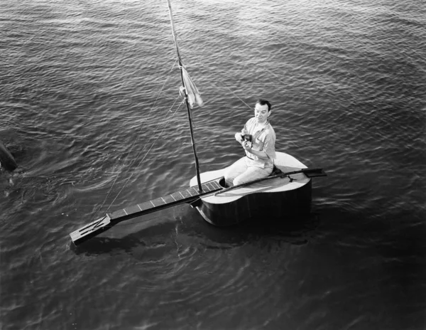 Uomo seduto su una barca a vela chitarra Foto Stock