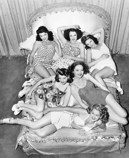 Six smiling young women lying on a bed Stock Photo