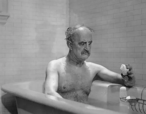 Homme dans la baignoire regardant le savon Photo De Stock