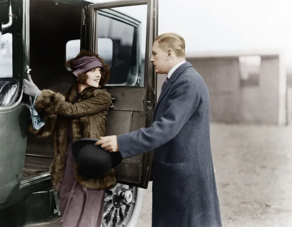 Профиль мужчины, помогающего молодой женщине сесть в машину — стоковое фото