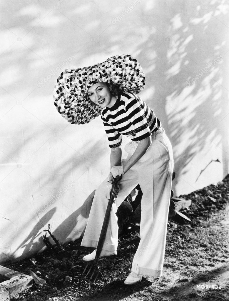 Woman with oversized hat digging in the garden