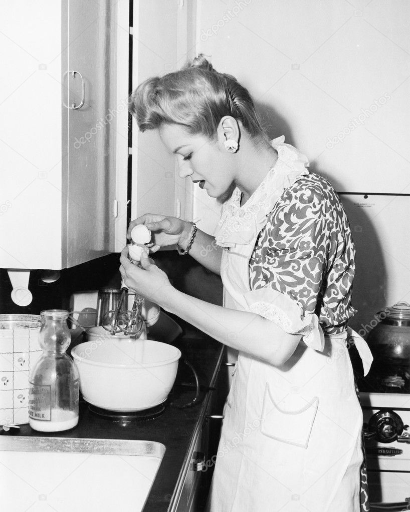Woman in the kitchen cracking an egg