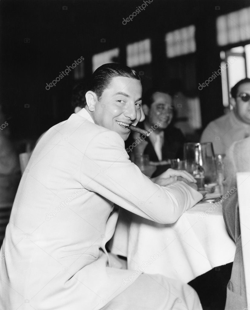 Smiling man with a cigar in his mouth in a restaurant