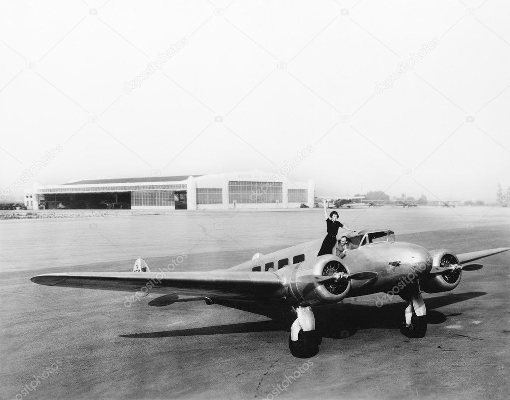 Woman standing on the propeller of an airplane waving