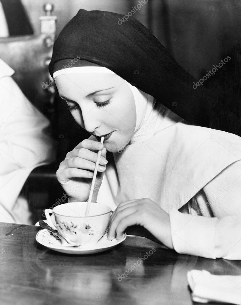 Nun sipping tea out of a teacup with a straw