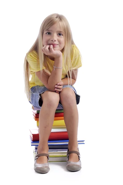Dziewczyna siedzi na stos książek — Zdjęcie stockowe